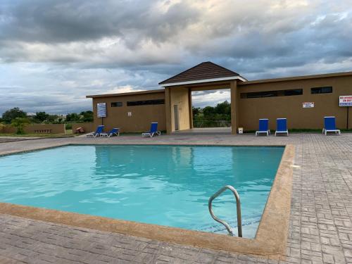 a swimming pool with chairs and a building at Harbour Oasis Retreat - Charming 2 Bedroom House in Old Harbour