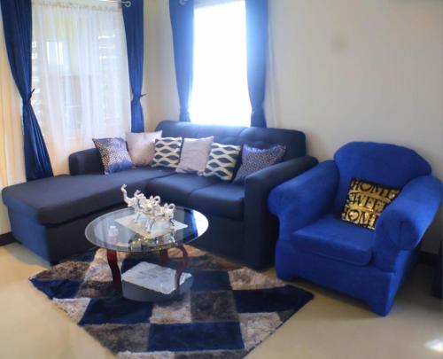 a living room with a blue couch and a glass table at Harbour Oasis Retreat - Charming 2 Bedroom House in Old Harbour