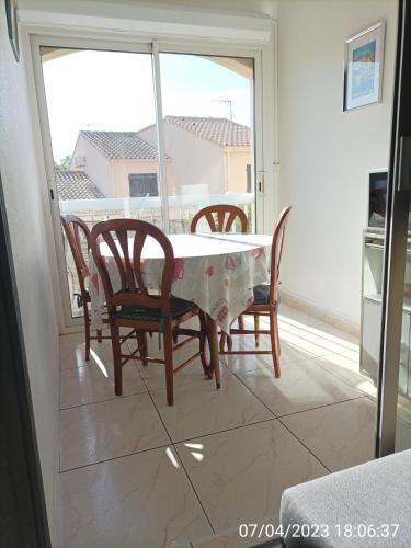 une salle à manger avec une table, des chaises et une fenêtre dans l'établissement Gîte Méditérranée, à Argelès-sur-Mer