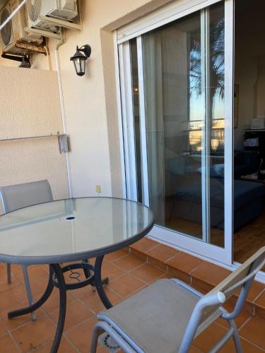 a glass table and chairs in a room with a window at Playa y paz in Benalmádena