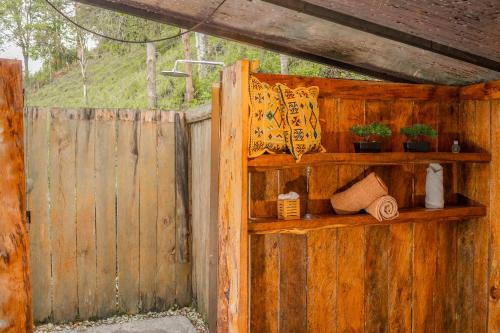 a wooden wall with shelves with plants and a fence at Riverside La Masía Ecohotel in Quindío