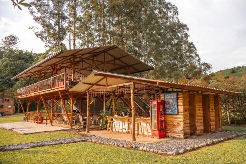 a large wooden building with a roof with a table at Riverside La Masía Ecohotel in Quindío