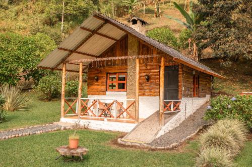 a small log cabin with a porch in a yard at Riverside La Masía Ecohotel in Quindío