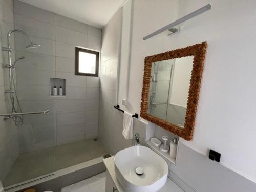 a bathroom with a sink and a shower and a mirror at Sunset Ocean View Apartment in Flic-en-Flac