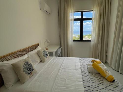 a bedroom with a large white bed with a window at Sunset Ocean View Apartment in Flic-en-Flac