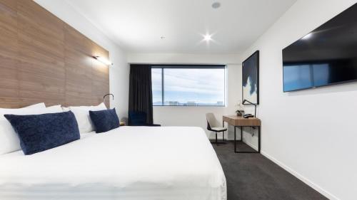 a bedroom with a large white bed and a desk at The Sebel Canberra Civic in Canberra