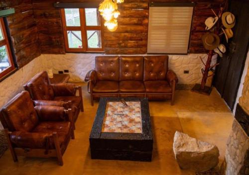a living room with leather furniture and a stone wall at Riverside La Masía Ecohotel in Quindío