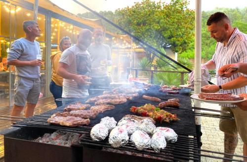 a group of people standing around a grill with meat at Hameau du Prat in Ribes