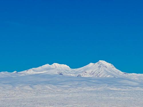 a snow covered mountain with a blue sky in the background at Aragats Hotel in Aragats