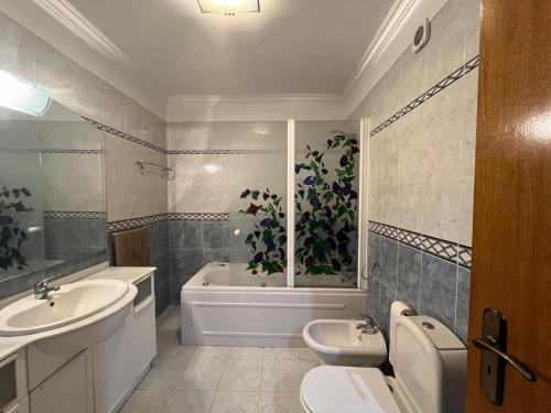a bathroom with a sink and a tub and a toilet at Casa Besugo in Sesimbra