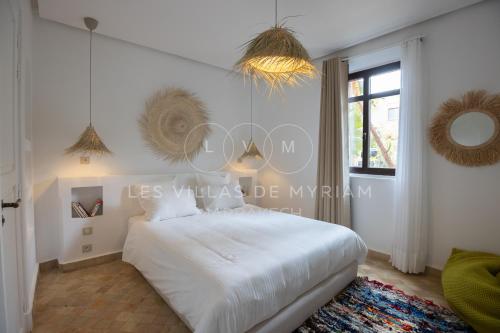 a bedroom with a white bed and a window at Dar Nadim sur le Golf de Samanah in Marrakesh