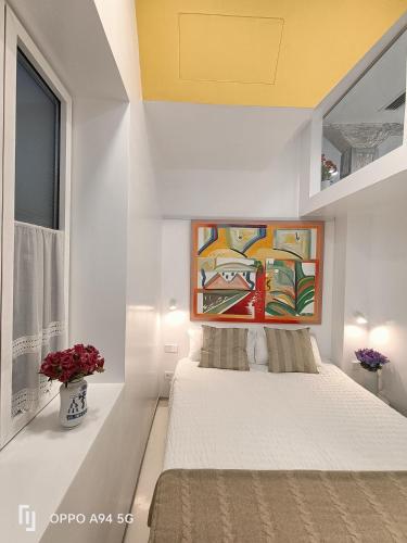 a white bedroom with a painting above a bed at San José y Maderuelo B in Ávila