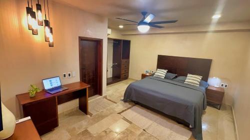 a bedroom with a bed and a desk with a laptop at Kasa Nikte Tulum in Tulum