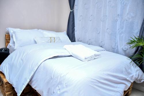 a bed with white sheets and towels on it at Elegant Studio with Rooftop Pool in Nairobi -Jovial Homes in Kiambu