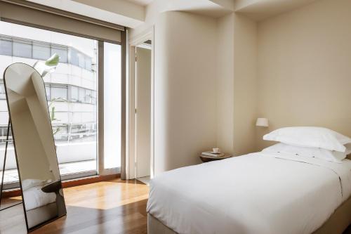 a bedroom with a white bed and a large window at Likno Athens in Athens