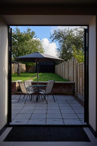a patio with a table and chairs and an umbrella at New Stylish 4-Bed-WiFi-Free Parking in Leamington Spa