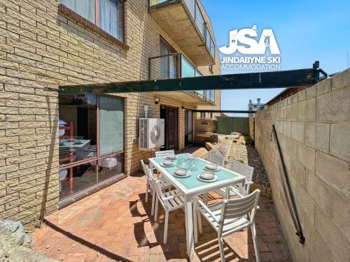 a patio with a table and chairs in front of a building at Central Park 2 in Jindabyne