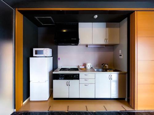 a small kitchen with white cabinets and a white refrigerator at AnsouHouseメゾネット 大阪ドーム in Osaka