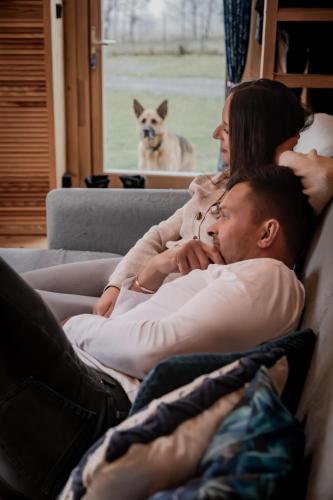 a man and a woman laying on a couch with a dog at Glamping Niebiańska Osada Jurty Dolnośląskie & SPA in Polanica-Zdrój