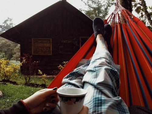 a person laying on a hammock with a cup of coffee at Cabañas Rusticas El Viejo Tambo in San Pedro