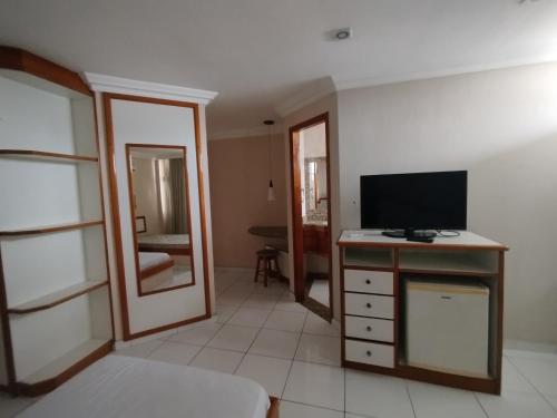 a living room with a television and a desk with a mirror at Slaass flat in Manaus