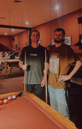 two men standing next to a pool table at On Top Backpackers in Dunedin
