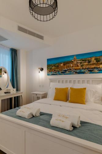 a white bedroom with a large bed with yellow pillows at Roel Boutique B&B in Cospicua