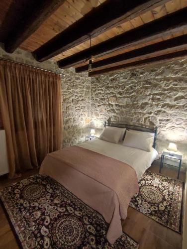 a bedroom with a bed and a stone wall at Drymaia Chalet in Amfikleia