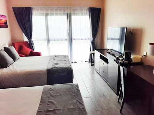 a hotel room with a bed and a television at Survivor Samoa Beach Resort in Falelatai