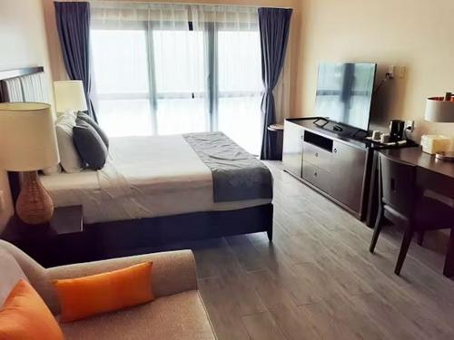 a bedroom with a bed and a desk and a couch at Survivor Samoa Beach Resort in Falelatai