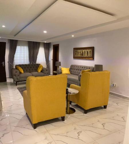 a living room with yellow chairs and couches at OD Cribs Luxury Apartment and On demand Car Service in Aso