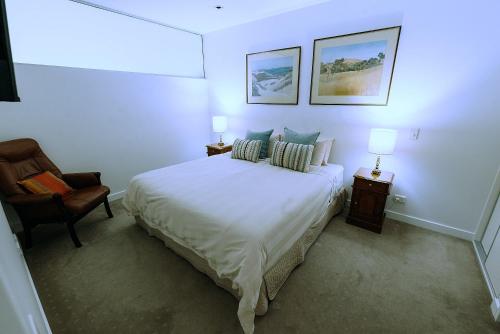 Un dormitorio blanco con una cama y una silla. en SEABREEZE at Victor Harbor, en Victor Harbor