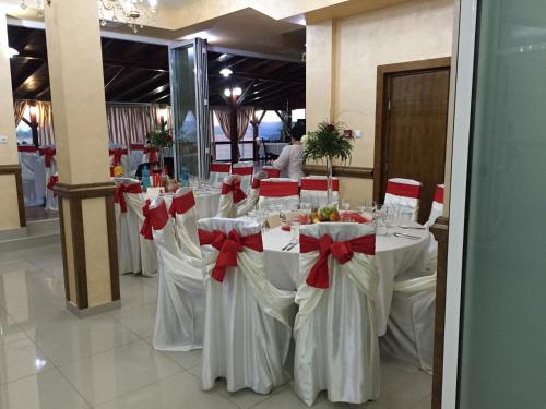 a group of tables with white chairs with red bows at Hotel Adial in Adjud