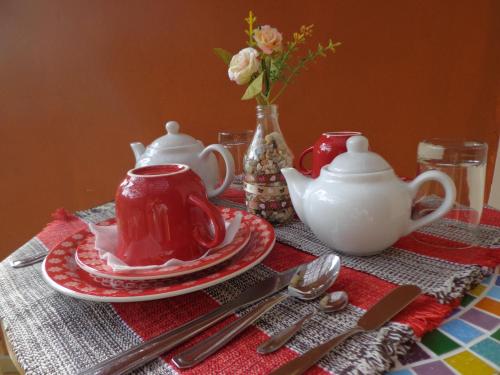 a table with a red and white tea set with silverware at Pousada Canto Bella Terra in Ilhabela