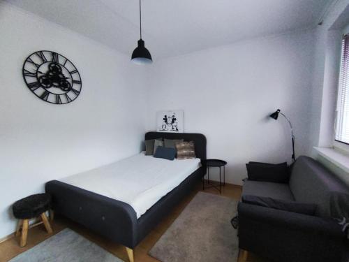 a bedroom with a bed and a couch and a clock at Your Home 7 with parking in Myslava
