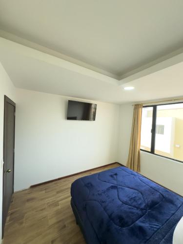 a bedroom with a blue bed and a window at San Benito B&B cerca Quito Aeropuerto - Tumbaco in Tumbaco