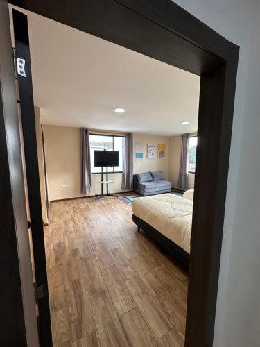 a bedroom with a bed and a couch and a television at San Benito B&B cerca Quito Aeropuerto - Tumbaco in Tumbaco