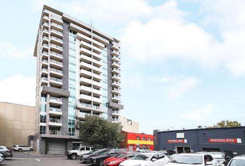 a tall building with cars parked in a parking lot at Amyra Residences at the Rowlands Apartments in Adelaide