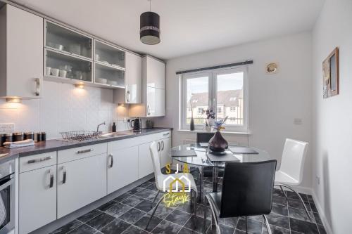 a kitchen with white cabinets and a table and chairs at Portland Pad - SJA Stays - Modern 2 Bed Apartment in Aberdeen