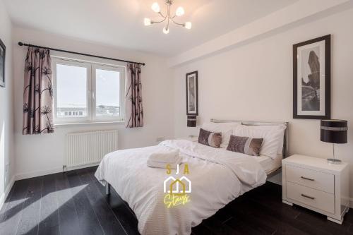 a white bedroom with a bed and a window at Portland Pad - SJA Stays - Modern 2 Bed Apartment in Aberdeen