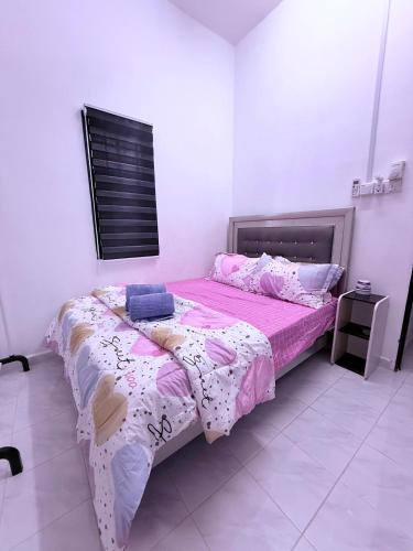 a bedroom with a large bed with pink and white sheets at De Bunga Homestay in Parit Raja
