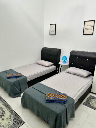 a room with two beds and a table at Pitaloka The Lakes Homestay in Batu Gajah