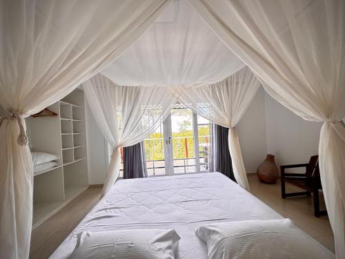 a bedroom with a white canopy bed with a window at Sunrise Paradise in Cayru
