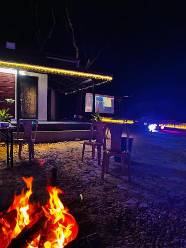 a fire in front of a table and chairs at night at RedBricks homestay, Coorg in Somvārpet