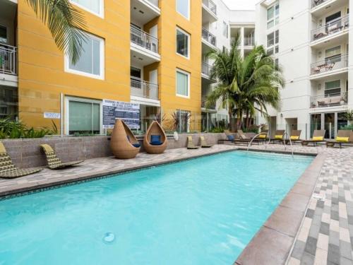 a large swimming pool with chairs and a building at West Hollywood 2bdr residence in Los Angeles
