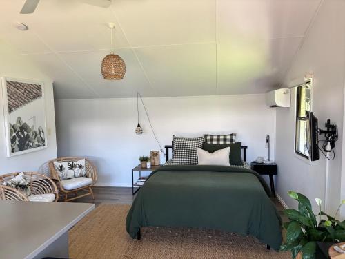 a bedroom with a green bed and a chair at Caba Beach Cabin in Cabarita Beach