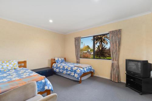 a bedroom with two beds and a tv and a window at Lakemere House in Kinloch