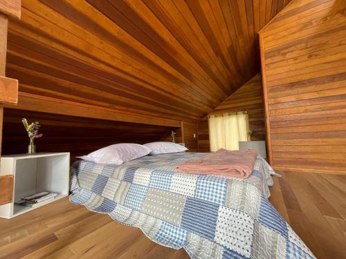 a bed in a room with a wooden ceiling at CHALÉ DOS ALPES VERDES in Canela