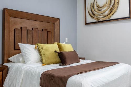 a bedroom with a bed with white sheets and yellow pillows at Exclusiva suite en el centro de Zapotlanejo 205 in Zapotlanejo