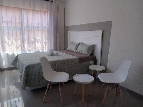 a bedroom with a bed with two tables and two chairs at Baksman's Retreat in Soweto